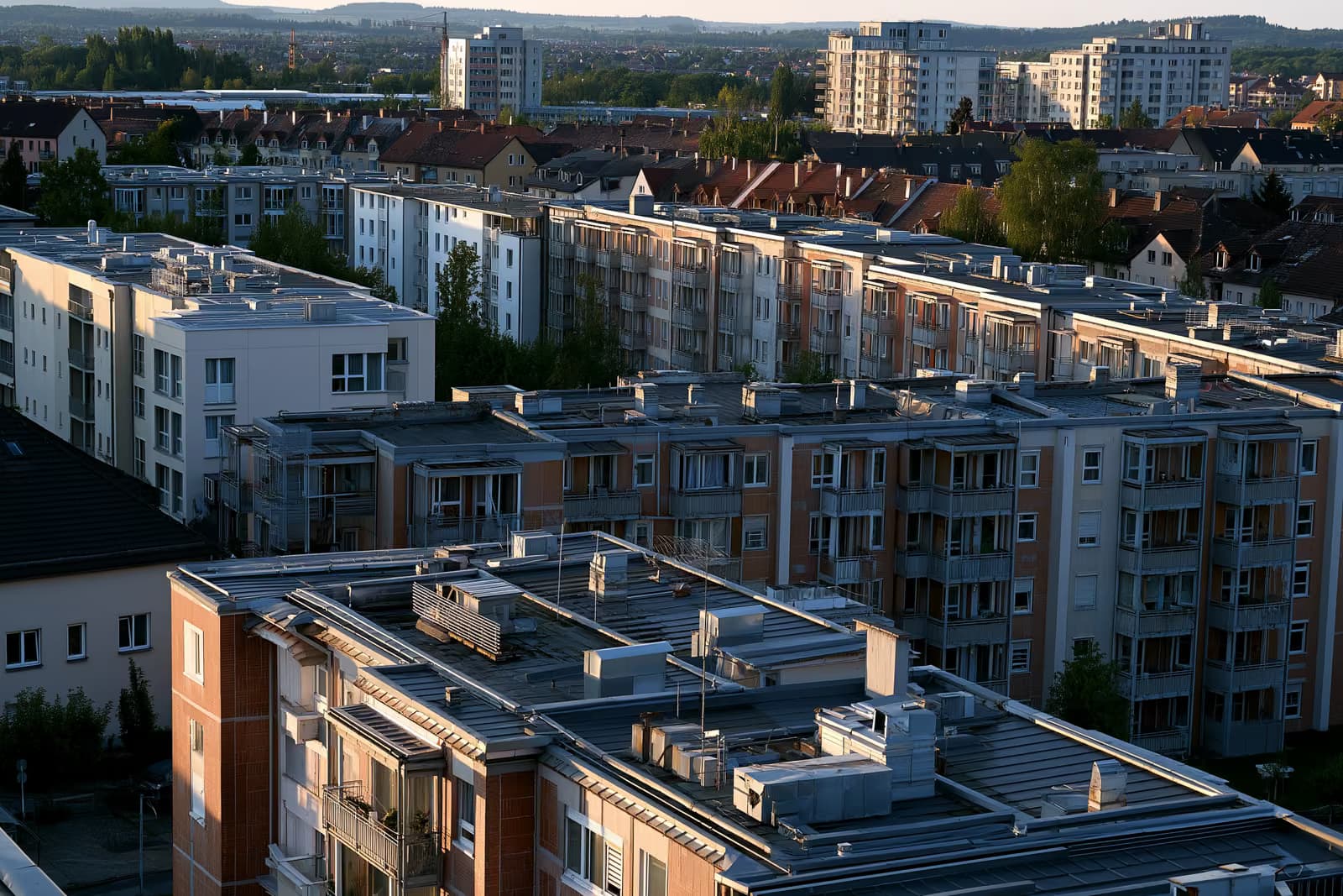 Çati dhe kanale ngrohjeje në ndërtesa apartamentesh banimi në një qytet gjerman nën dritën e ngrohtë të pasdites.